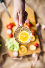 Woman's hand holding a glass of fresh lemon water