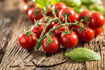 Fresh bunch of ripe tomatoes with basil leaves on old oak table