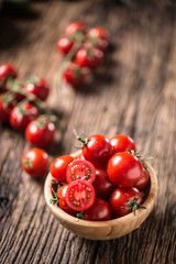 Fresh cherry tomatoes in wooden bowl on old oak table