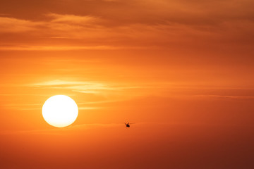 Fototapeta premium Sunset orange sky background at evening with clouds and silhouette of the helicopter