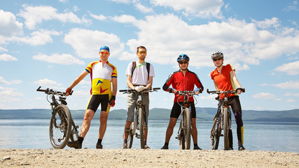 group of cyclists on the shore of a mountain lake. man outdoors. mountain bike.