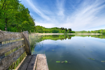 bench on the footbridge over the lake during a sunny day. Spring calm landscape. Masuria, Poland