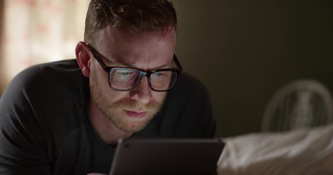 4K Closeup Caucasian man with glasses staring at tablet with serious expression. Slow motion.