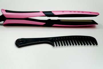 Rose hair straightener with black comb on white. Hair care