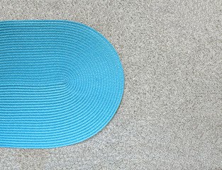 Fototapeta na wymiar Blue woven napkin on stone background. Oval mat for placing plates on stone tile surface top view.