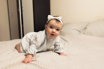 Fototapeta premium Cute newborn girl lying on the bed. The baby wants to sleep in the parent's bed.