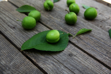 Green fresh plums on the wooden background