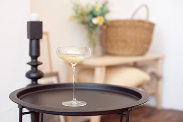 Full glass of champagne with white wine or champagne stands on a black matte tray in the room
