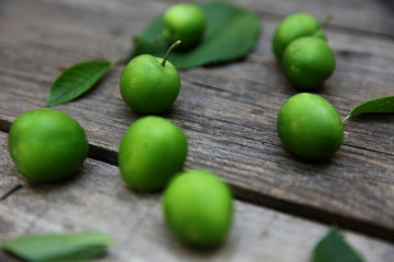 Green fresh plums on the wooden background