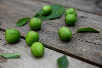 Green fresh plums on the wooden background