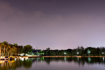 Fototapeta na wymiar Horizontal view of lake and nature during dusk with night stars and smooth reflection on waters