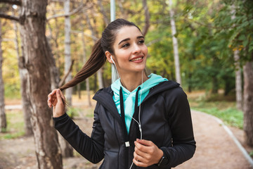 Smiling fitness woman listening to music with earphones