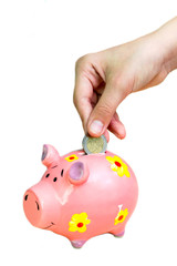 Girl put coin two euro into pink piggy bank. Hands close-up.