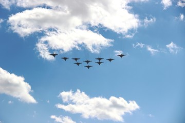 Ten planes in a blue sky with clouds on a Sunny day, selective focus. A group of ten aircraft in a blue sky with white clouds.