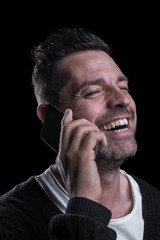 Side studio portrait of a smiling man with mobile phone. Isolated on black background. Vertical.