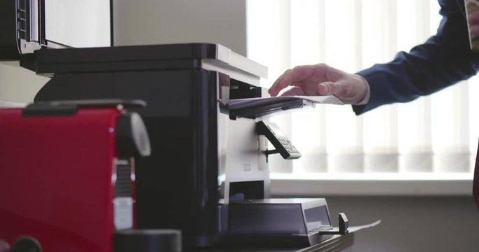 Close up young businessman takes document from photocopying machine
