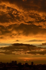 夕焼けに燃えるような雲と街のシルエット