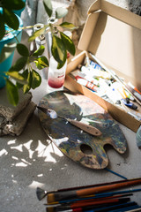 Paint brushes and assorted paints on the floor of artist's studio