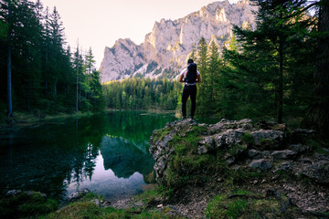 Fototapeta na wymiar Beautiful green lake in austria with a hiker standing on a rock
