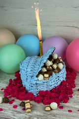 homemade heart shaped like a box blue-violet cake with chocolate pralines and coconut, decorated with pink flowers and colorful balloons
