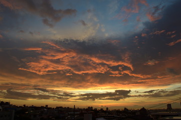 夕焼けに燃えるような雲と街のシルエット