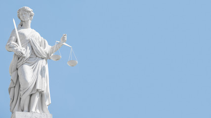 Statue a judge woman with scales and sword at blue sky in Potsdam, Germany