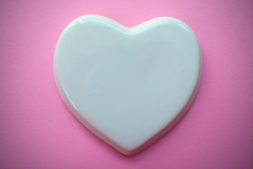  White glossy porcelain heart on a pink background; Wedding card; A love note. Copy space