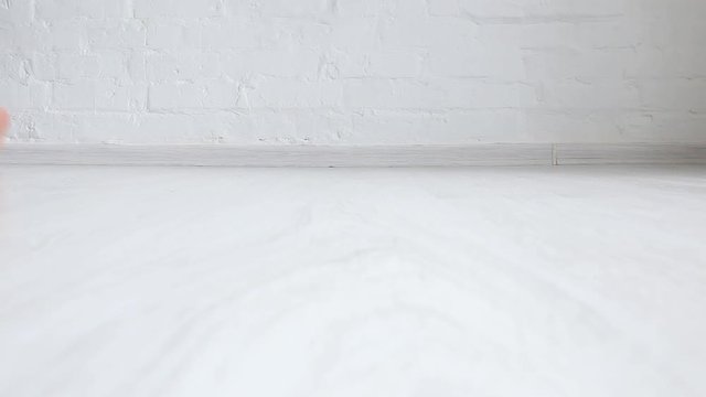 A child in jeans walks on the white floor. Feet close up.