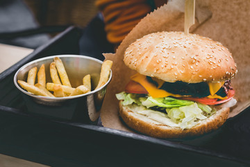Fresh delicious burger with french fries on the black wooden table