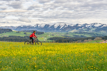 Fototapeta na wymiar senior woman mountainbiking on a e-mountainbike in early spring, in the Allgaeu Area, a part of the bavarian alps,Germany