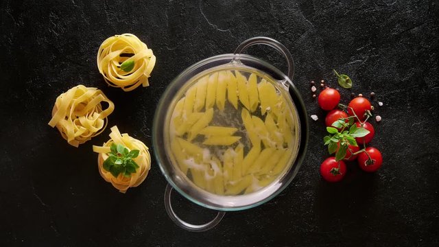 Cooking pasta penne in a glass pot with boiling water
