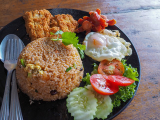 fried rice with fried chicken egg, sausages and salad on wooden table.