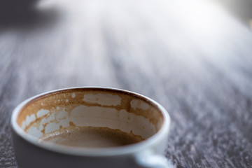 white cup of coffee with half full of coffee and bubble foam.