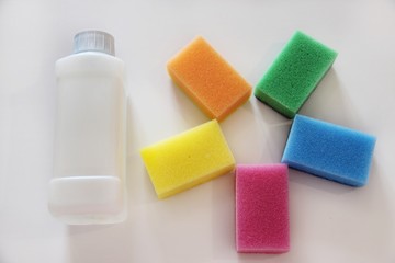 Cleaning sponges in the form of the sun and a bottle of plastic, liquid detergent on a white background