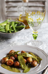 fried early summer vegetables - young potatoes (baby potatoes) and young green peas. summer vegetables on a gray plate.