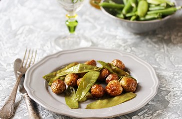 fried early summer vegetables - young potatoes (baby potatoes) and young green peas. summer vegetables on a gray plate.