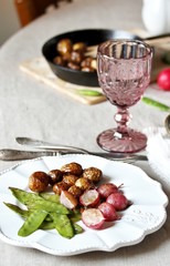 young summer vegetables-fried radish, young peas and young potatoes. dinner served at the table, beautiful table setting.