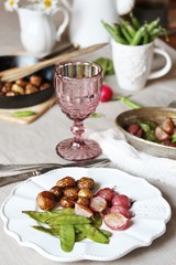 young summer vegetables-fried radish, young peas and young potatoes. dinner served at the table, beautiful table setting.
