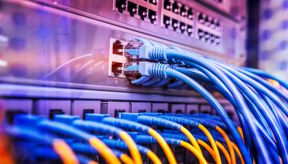 Server rack with blue and red internet patch cord cables connected to black patch panel in data...