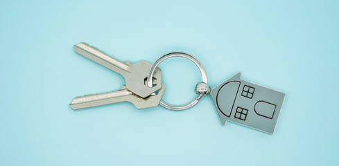 key chain with house symbol and keys on blue background,Real estate concept