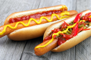 Two hot dogs closeup with ketchup , yellow mustard and chili on gray wooden table