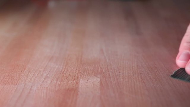 Close-up on man's hand grinding wooden table.
