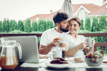 Attractive husband kissing his wife during breakfast in the garden