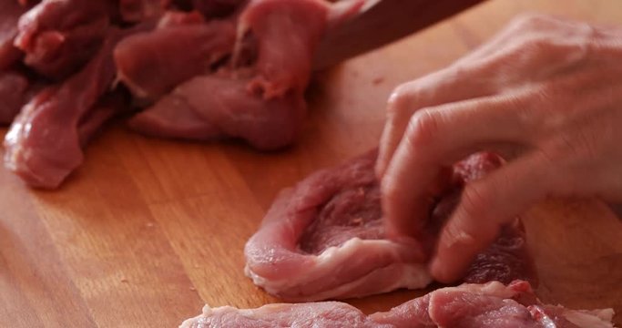 Pork steaks chopped onto thin slices using sharp knife, close-up