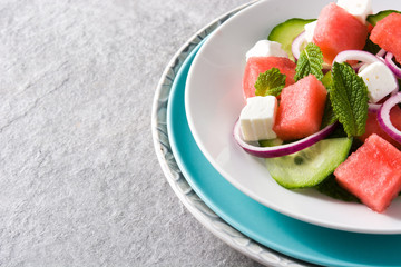 watermelon salad with feta cheese,mint,onion and cucumber on gray background. Copyspace