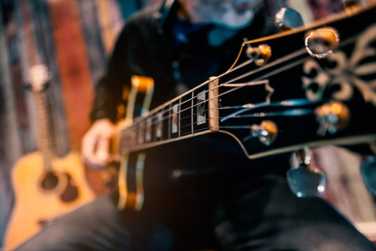 musician playing an electric guitar chord harmony composer song writter sound recording session wood instrument magic feel strings on a blur background rock blues jazz lesson class learn practice