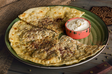 Traditional Azerbaijani cuisine. Qutab with meat and cheese on a plate. Closeup