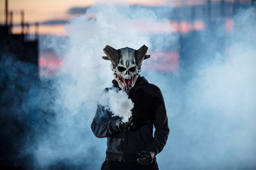 Devil with scary mask surrounded by white smoke