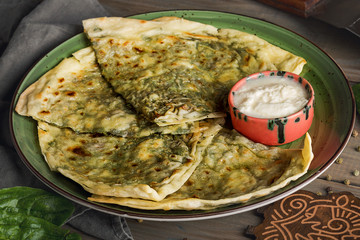 Azerbaijani cuisine. Qutab with greens, spinach and cheese on a plate. Closeup