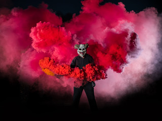 Devil with scary mask surrounded by red smoke